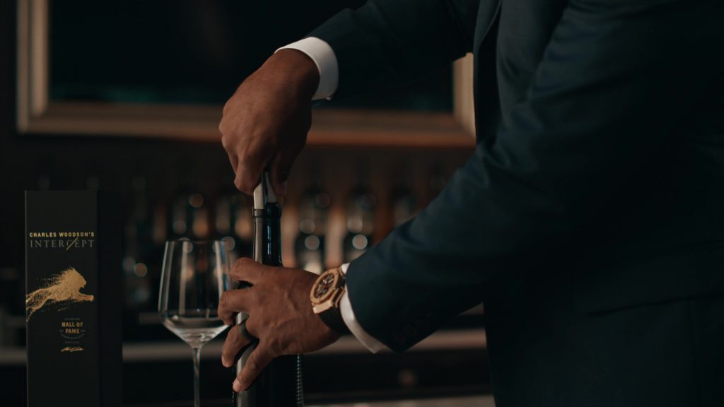 Intercept Wines Case Study Photo 10 Person in a suit using a corkscrew to open a wine bottle labeled 'Charles Woodson's Intercept Hall of Fame.